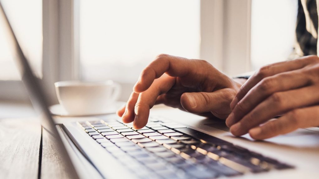 Digital marketing strategy for small business owner working on laptop with coffee in bright office