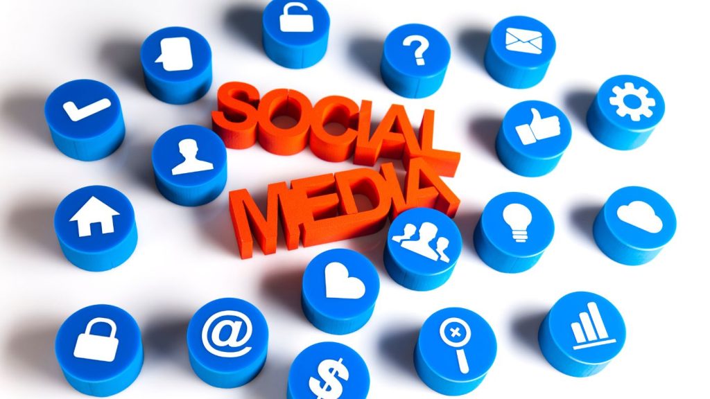 Social media marketing icons including thumbs up, home, email, and question mark symbols surrounding bold 3D text reading 'SOCIAL MEDIA' representing social media marketing for small business