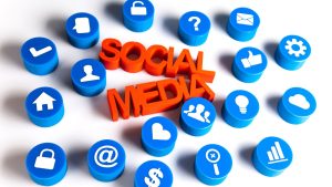 Social media marketing icons including thumbs up, home, email, and question mark symbols surrounding bold 3D text reading 'SOCIAL MEDIA' representing social media marketing for small business